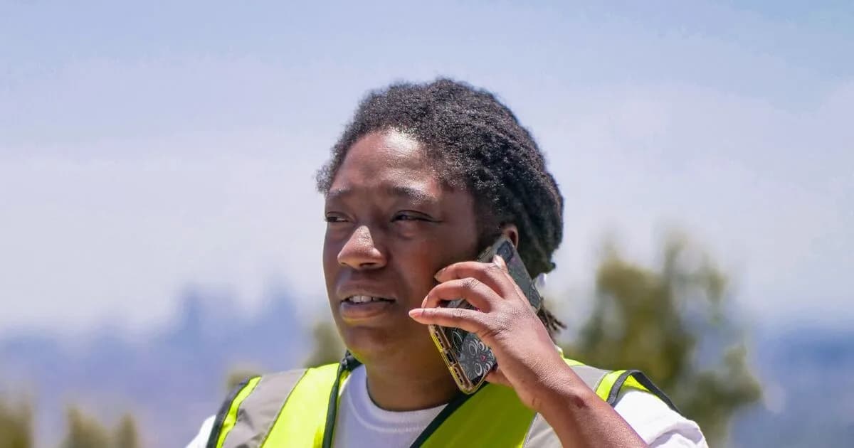Connecticut contractor in a high-visibility vest checking their business website on a phone at a job site