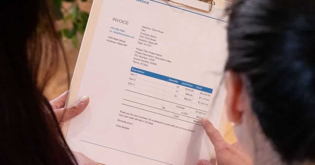 Two people reviewing an itemized invoice with cost breakdown on a clipboard